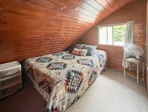 Cozy cabin room with a bed, chair, and storage unit, perfect for a relaxing stay.