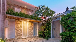 Ein zweistöckiges Haus mit einer Stein-Fassade, einem Balkon und einer gepflasterten Terrasse.