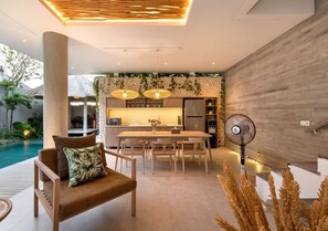 A modern kitchen with a dining area, a pool, and a lounge area with a sofa and a fan. - 2 Bedroom Villa In Seminyak With Private Pool (Bali)