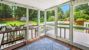 A covered porch with a wooden bench, a blue patterned rug, and potted plants. - Quaint Cottage of Holly Springs (Holly Springs)
