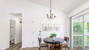 A dining area with a round table, chairs, a chandelier, and framed artwork on the wall. - Quaint Cottage of Holly Springs (Holly Springs)