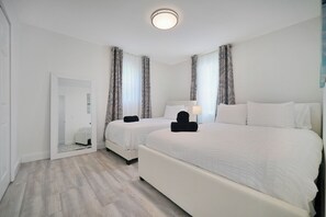 Habitación de hotel con dos camas, un espejo grande y una lámpara en el techo.