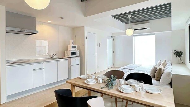 Una cocina moderna con armarios blancos, una mesa de comedor lista para cuatro comensales y un techo con vigas a la vista.