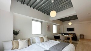 Una habitación de hotel moderna con una cama grande, un comedor y un televisor.