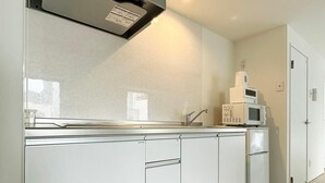 Una cocina moderna con armarios blancos, una campana extractora de acero inoxidable y un microondas en la encimera.