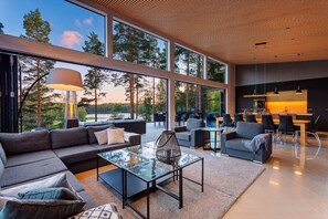 A modern interior with a large glass window, a sofa, a coffee table, and a dining area.