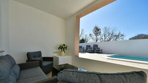 A modern living room with wicker furniture, a small table, and a potted plant.