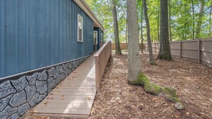 Eine Holzterrasse führt zu einem blauen Gebäude mit einer Steinmauer als Fundament.