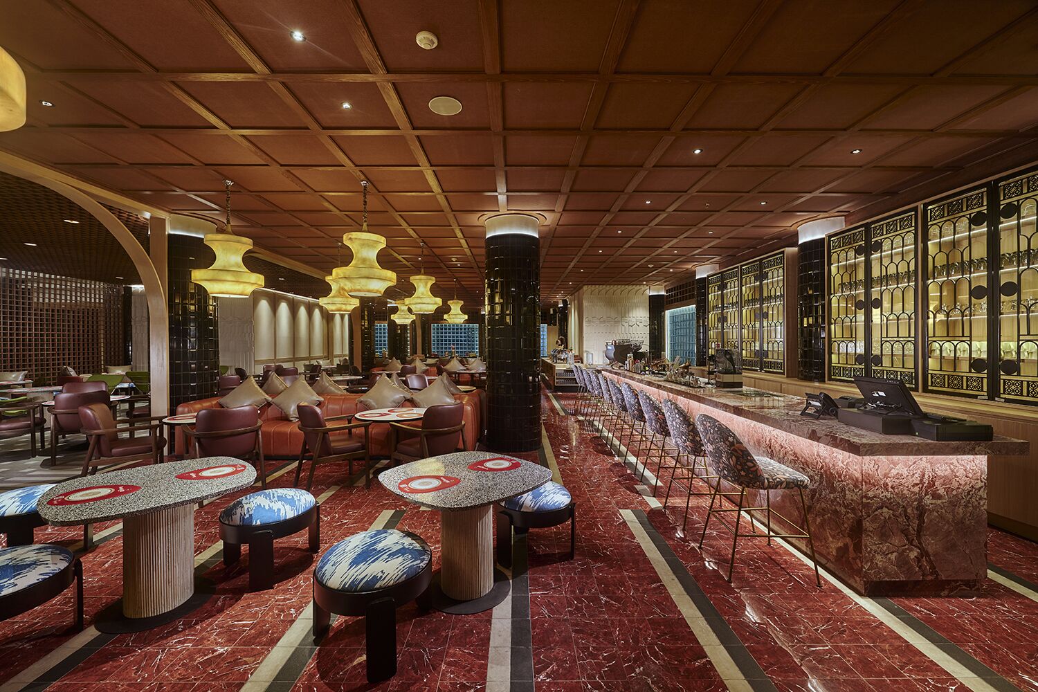 A spacious restaurant with high ceilings, multiple seating areas, and a bar counter.