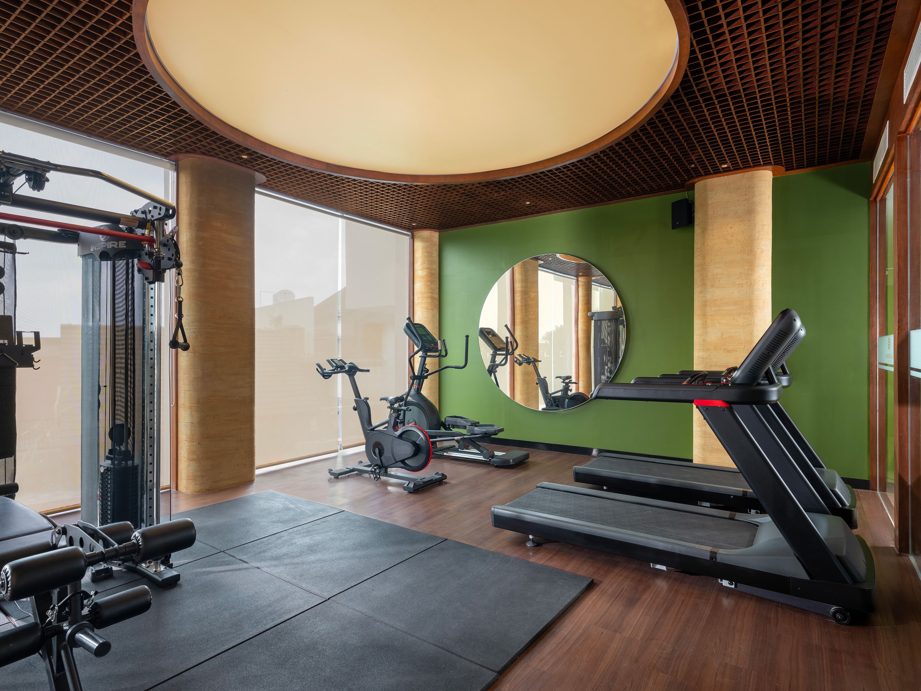 A gym with exercise equipment, a large mirror, and a wooden ceiling.