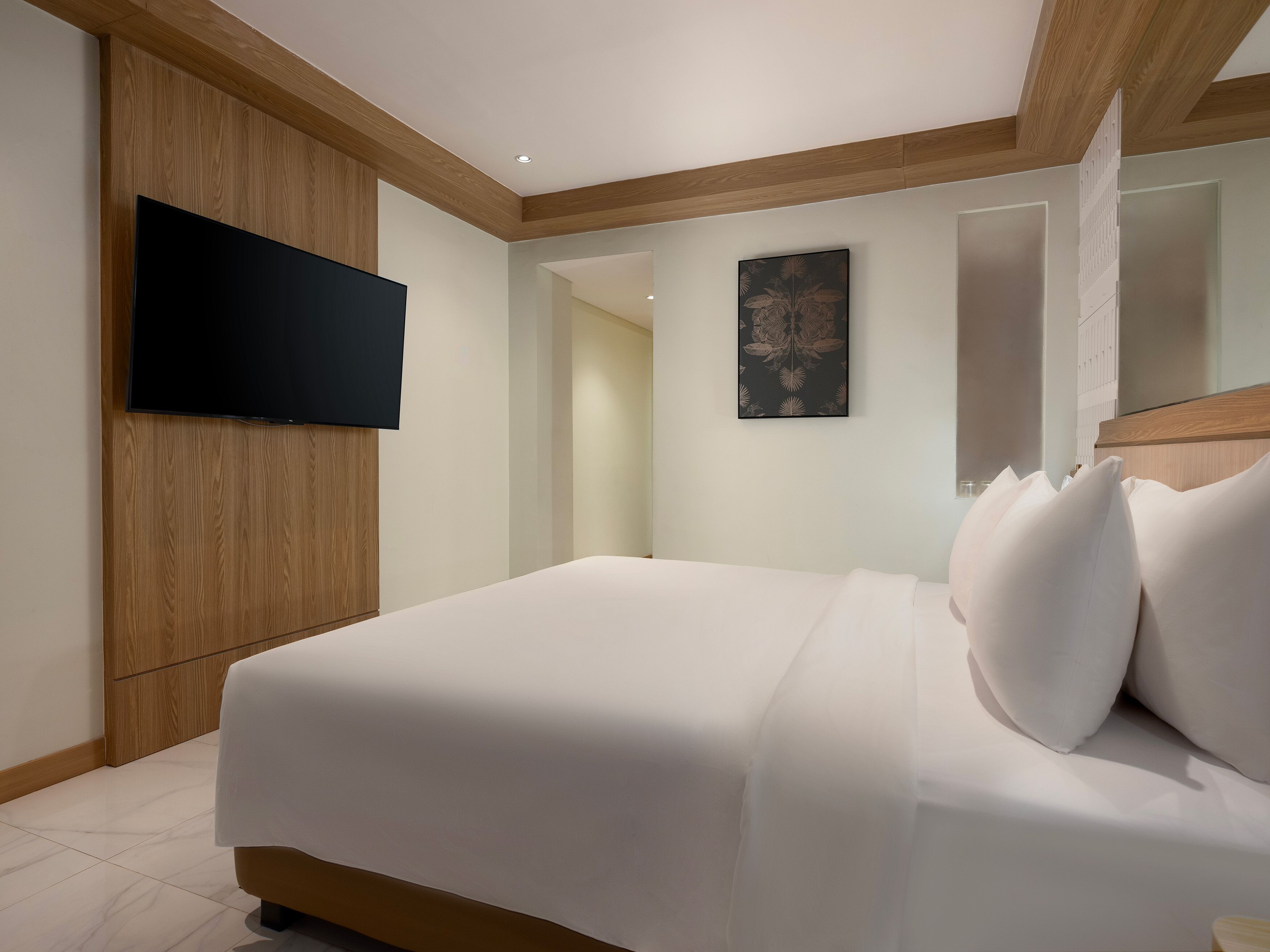 A modern bedroom with a large bed, wooden paneling, a flat-screen TV, and a mirror.
