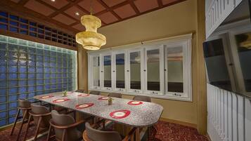 A dining area with a marble floor, a long table with chairs, a hanging light fixture, and a large window with frosted glass panels.
