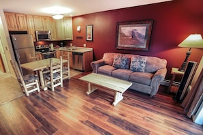 A compact living space with a kitchenette, a sofa, a dining table, and a lamp. - Fawn Valley Inn: 298 1 Bedroom Condo (Estes Park)