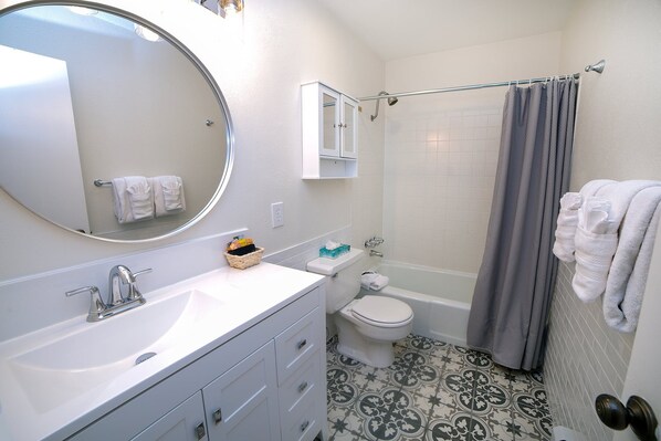 A bathroom with a white sink, a toilet, a bathtub, and a shower curtain.