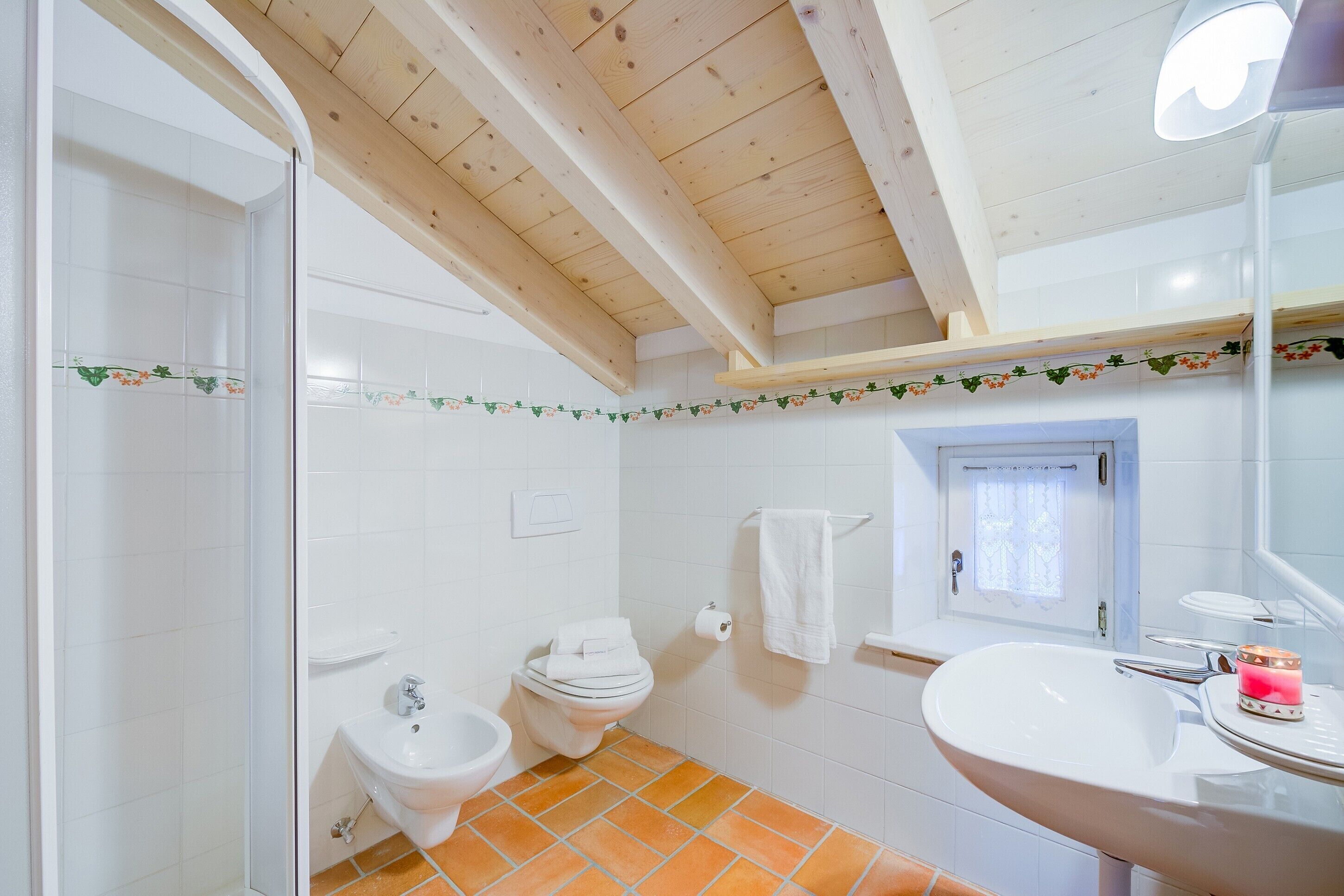A bathroom with a shower, toilet, bidet, sink, and a mirror.