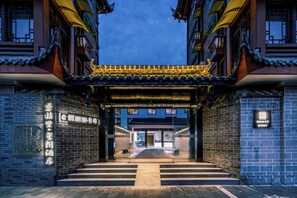 A traditional Chinese gate with a modern entrance, brick walls, and a clear pathway leading inside. - Gongxili - Xige Hotel (Chengdu)