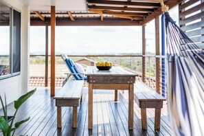 An outdoor wooden deck with a table and benches, a hammock, and a bowl of lemons. - Little Beachies - Oceanstays (Angourie)
