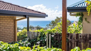 A house with a brick exterior, a wooden fence, and a view of the ocean. - Little Beachies - Oceanstays (Angourie)