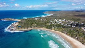 An aerial view of a coastal area with a beach, a small town, and a clear blue ocean. - Little Beachies - Oceanstays (Angourie)