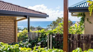 A house with a brick exterior, a wooden fence, and a view of the ocean. - Beachies - Oceanstays (Angourie)