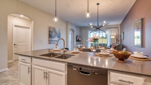 A modern kitchen with a central island, stainless steel appliances, and pendant lighting.