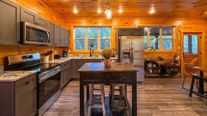 A modern kitchen with wooden walls, stainless steel appliances, and a central island.