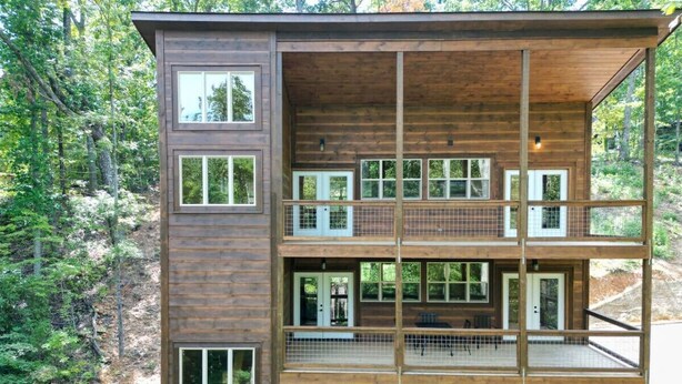 A multi-story wooden cabin with balconies, surrounded by forest.