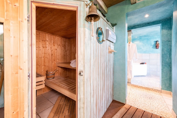A wooden sauna room with benches, a bell, and a mirror.