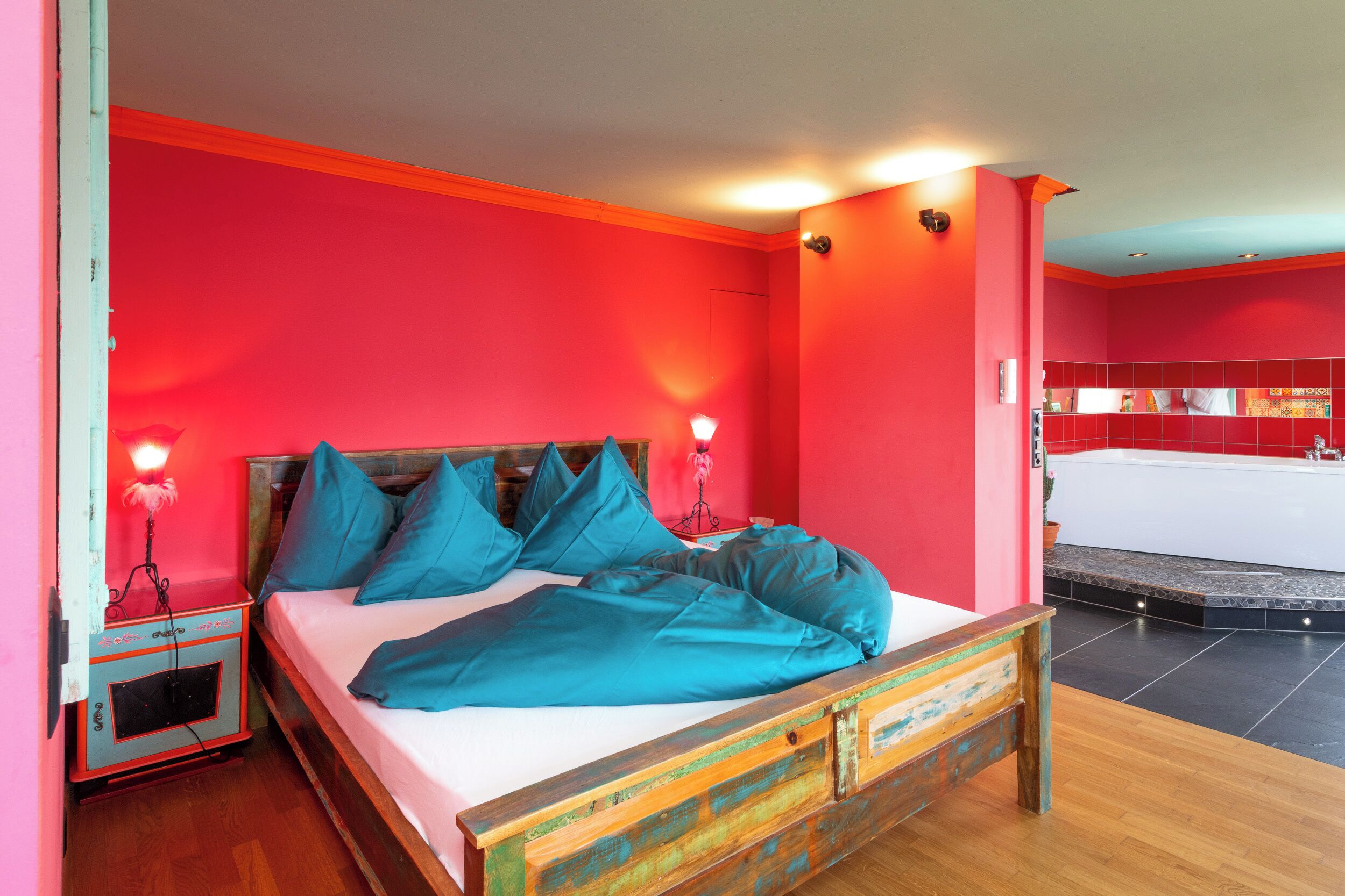 A bedroom with a wooden bed, teal bedding, and red walls.