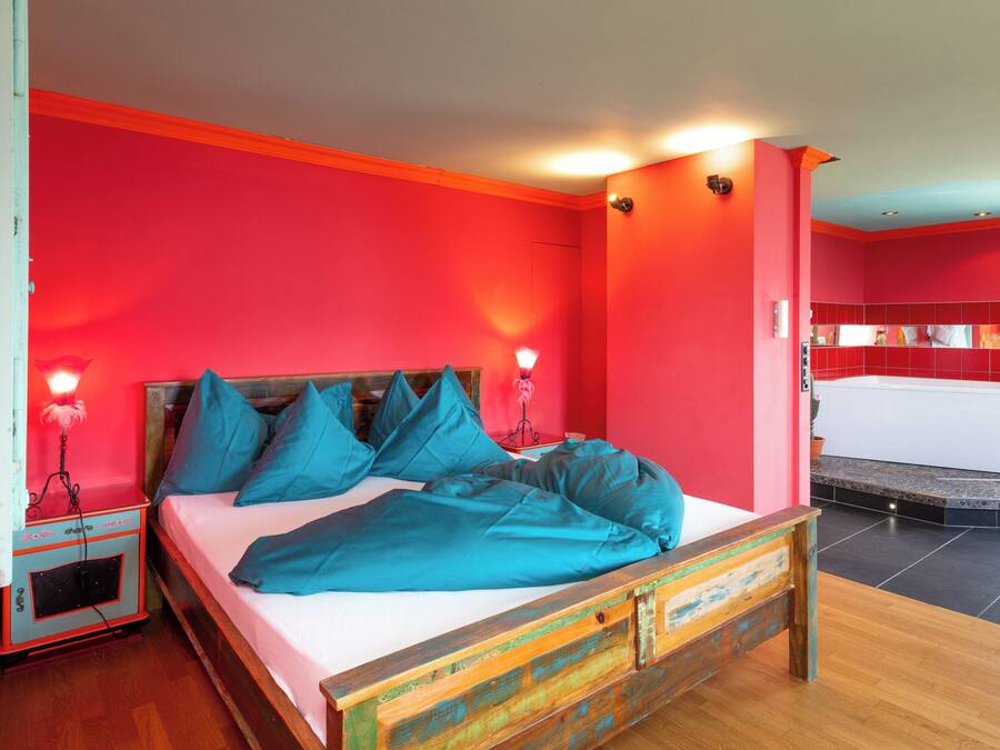 A bedroom with a wooden bed, teal bedding, and red walls.