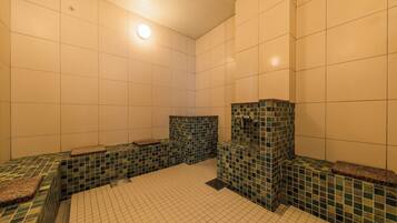 A tiled bathroom with a sink, mirror, and bench seating.