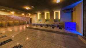 A spacious indoor area with a stone wall, multiple benches, and a blue-lit wall feature.