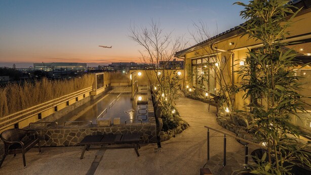 A rooftop pool area with stone steps, seating, and potted plants.