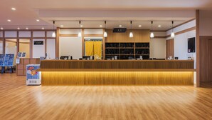 A reception area with a wooden reception desk, a vending machine, and a yellow curtain.