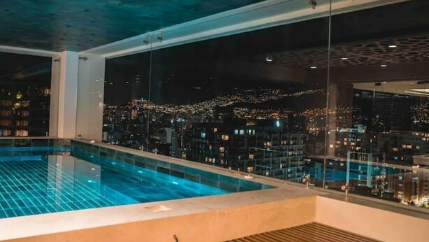 Ein Pool auf dem Dach mit Blick auf die beleuchtete Stadt.