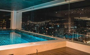 A rooftop pool with a city view at night. - Departamento de Lujo Penthouse (Quito)