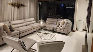 Ein modernes Wohnzimmer mit Ecksofa, Glastisch und minimalistischer Einrichtung.