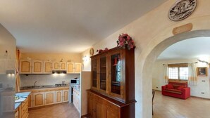 A spacious kitchen with wooden cabinets and a built-in microwave. - Vacation home Fusco by Interhome (Olbia)