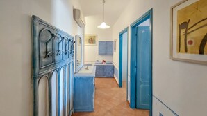 A hallway with a blue door, a sink, and a mirror. - Vacation home Fusco by Interhome (Olbia)