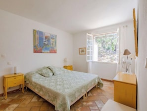 Una camera da letto con un letto, un comodino, una cassettiera, una finestra e un quadro appeso al muro.