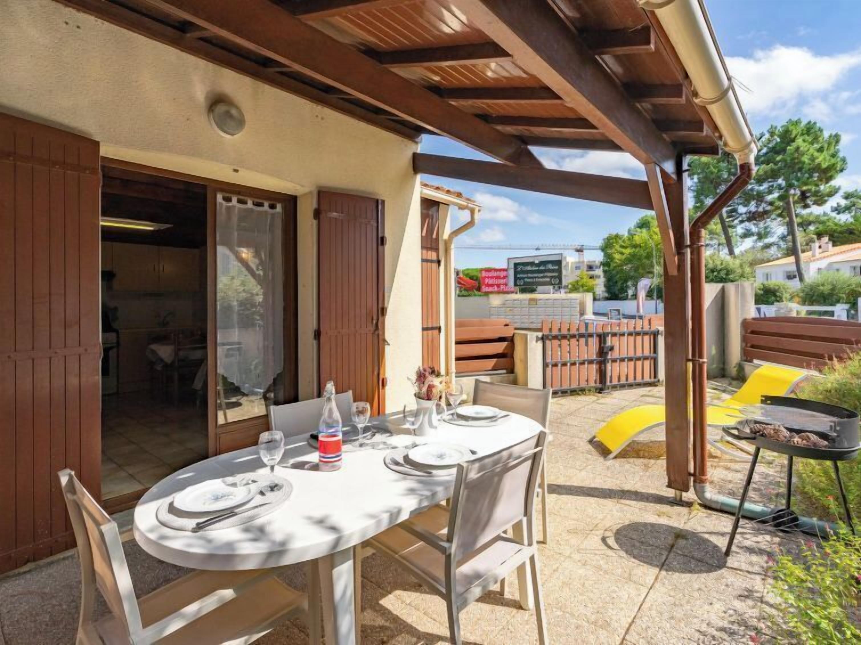An outdoor dining area with a table set for two, a grill, and a view of the surrounding area.