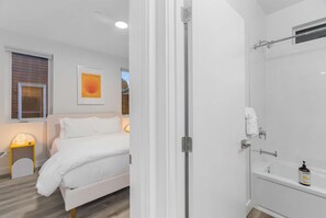 Une chambre à coucher avec un lit, une lampe de chevet, une fenêtre avec des stores et une affiche accrochée au mur.