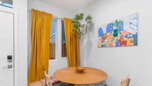 A dining area with a round wooden table, green cushioned chairs, and yellow curtains. - Cozy Oasis in the heart of Capitol Hil (Seattle)