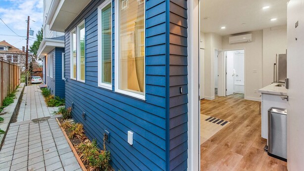 A modern house with a blue exterior, a visible garage door, and a clean, well-lit interior with a kitchen area. - Cozy Oasis in the heart of Capitol Hil (Seattle)
