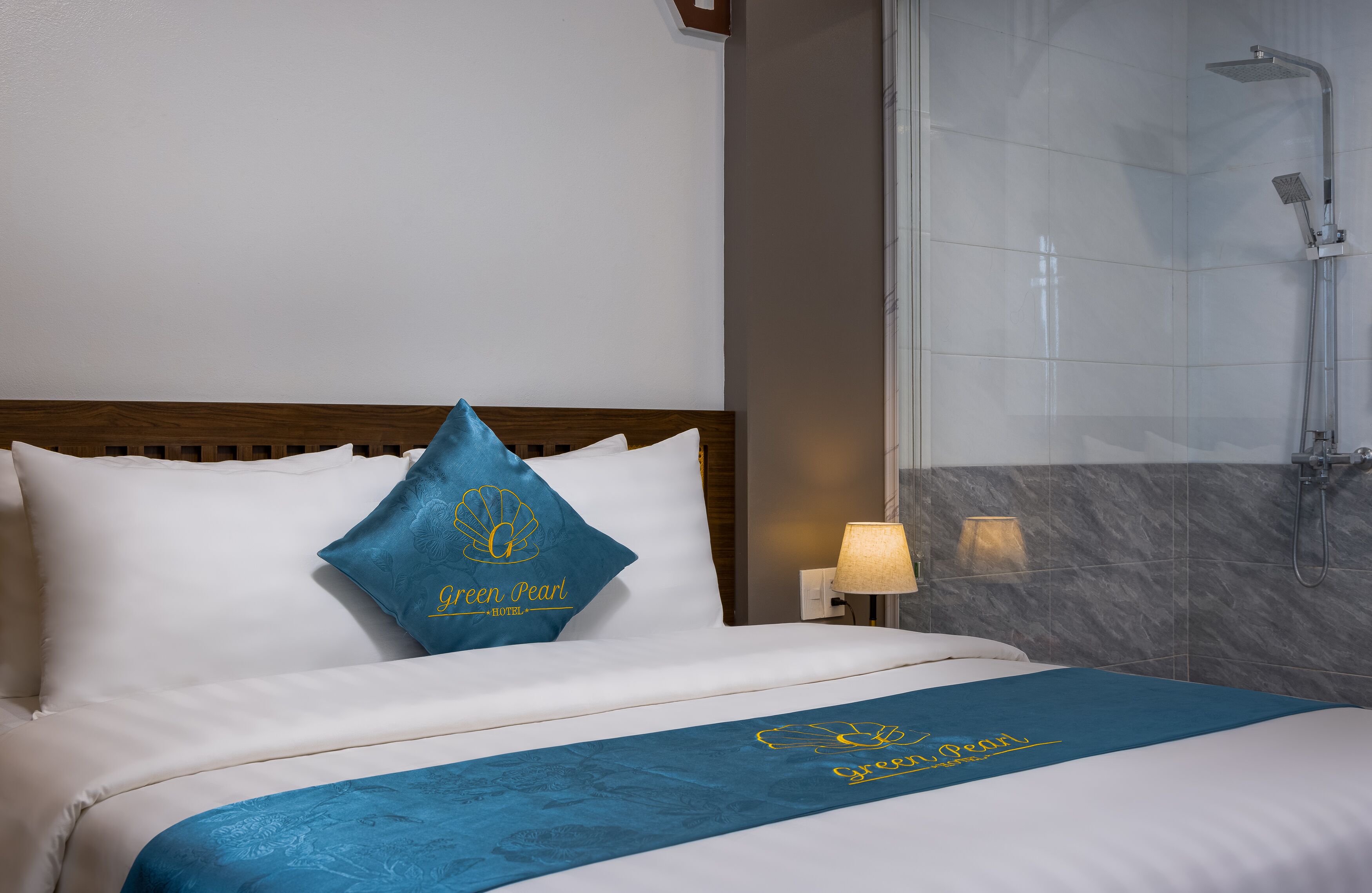 A hotel room with a bed, a shower, and a nightstand with a lamp.