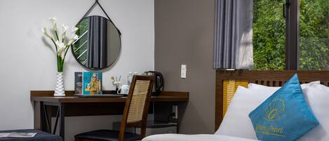 A hotel room with a bed, a desk, a chair, a mirror, and a window with curtains.