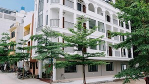 A multi-story building with balconies and large windows, surrounded by greenery. - Cat Ba Green Pearl Hotel (Hai Phong)