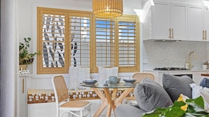 Een moderne keuken met een eethoek, met een ronde glazen tafel, witte stoelen en een inbouwbank.