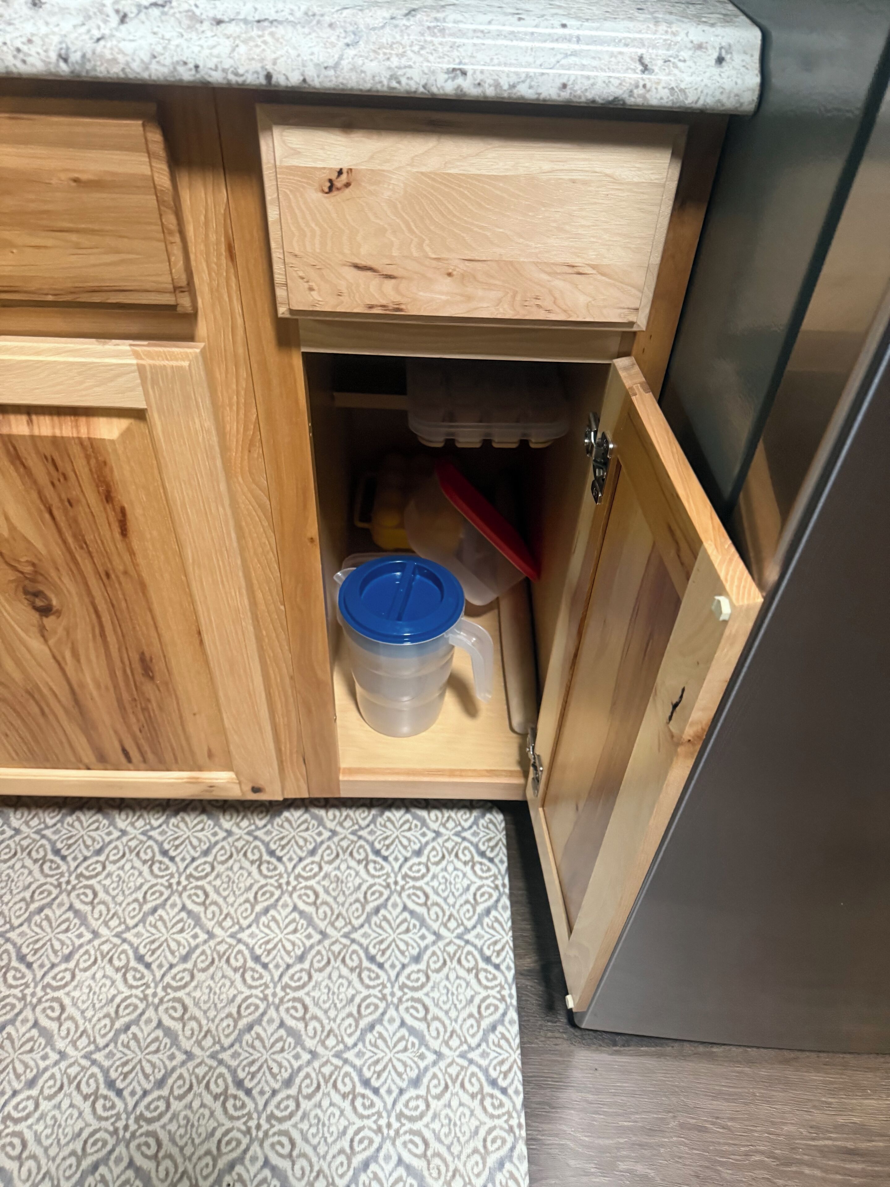 Ein Küchenschrank aus Holz mit integriertem Mülleimer und einem blauen Behälter.