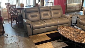 En moderne stue med en lædersofa, et sofabord og et spiseområde med et træbord og stole.